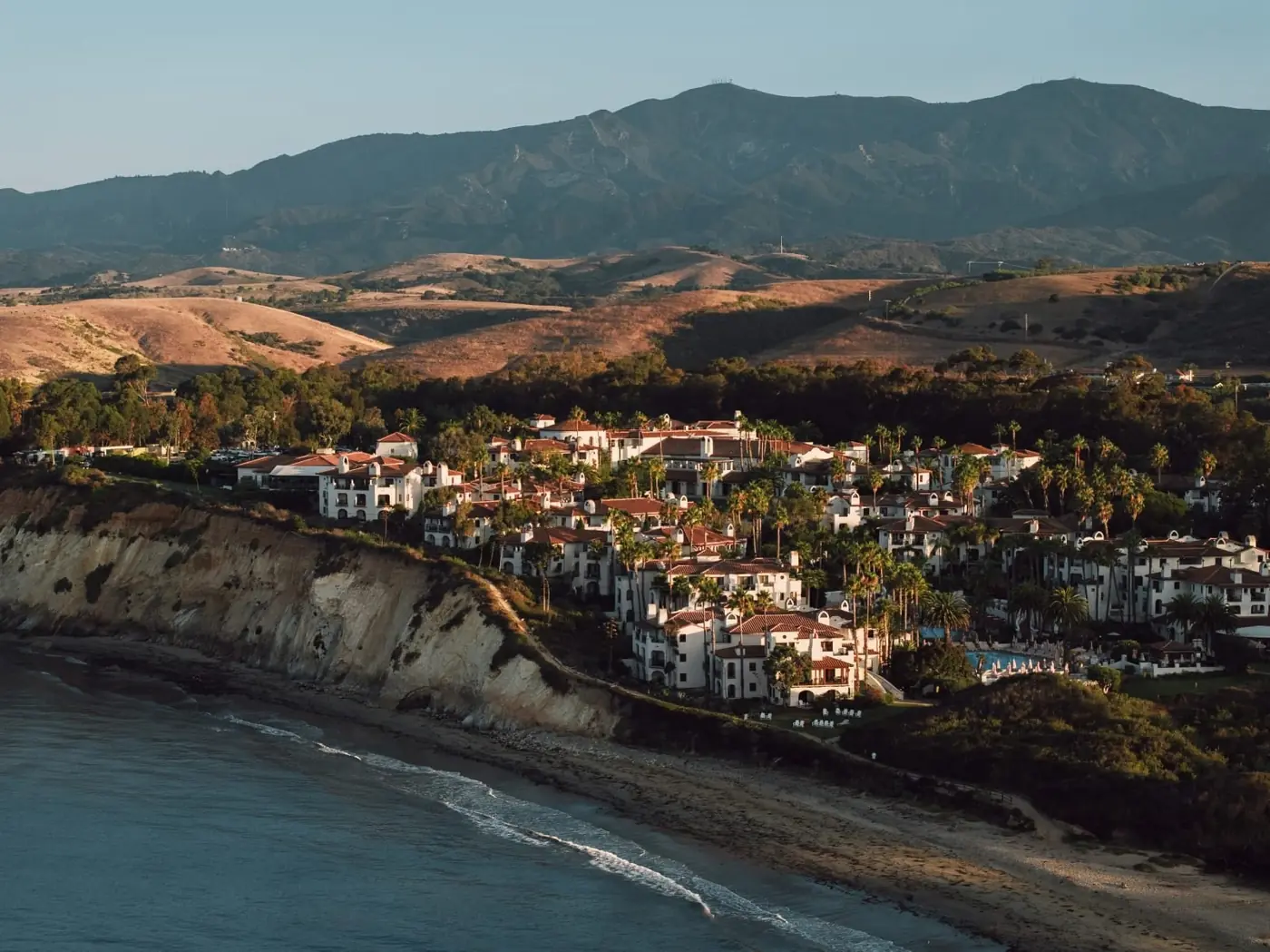 A pastel seaside village stacked above the water at golden hour