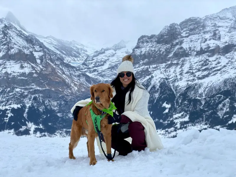 Vania with a dog in the snowy Swiss mountains