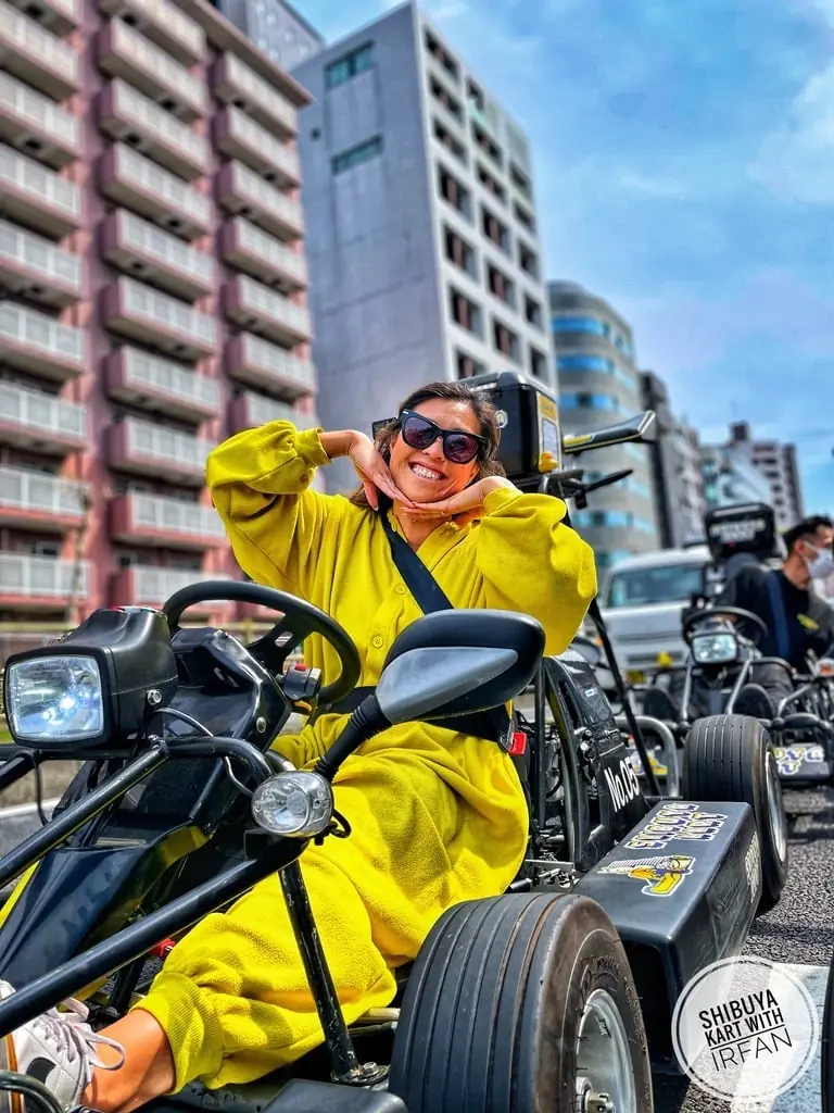 Vania go-karting through the streets of Tokyo in a yellow suit